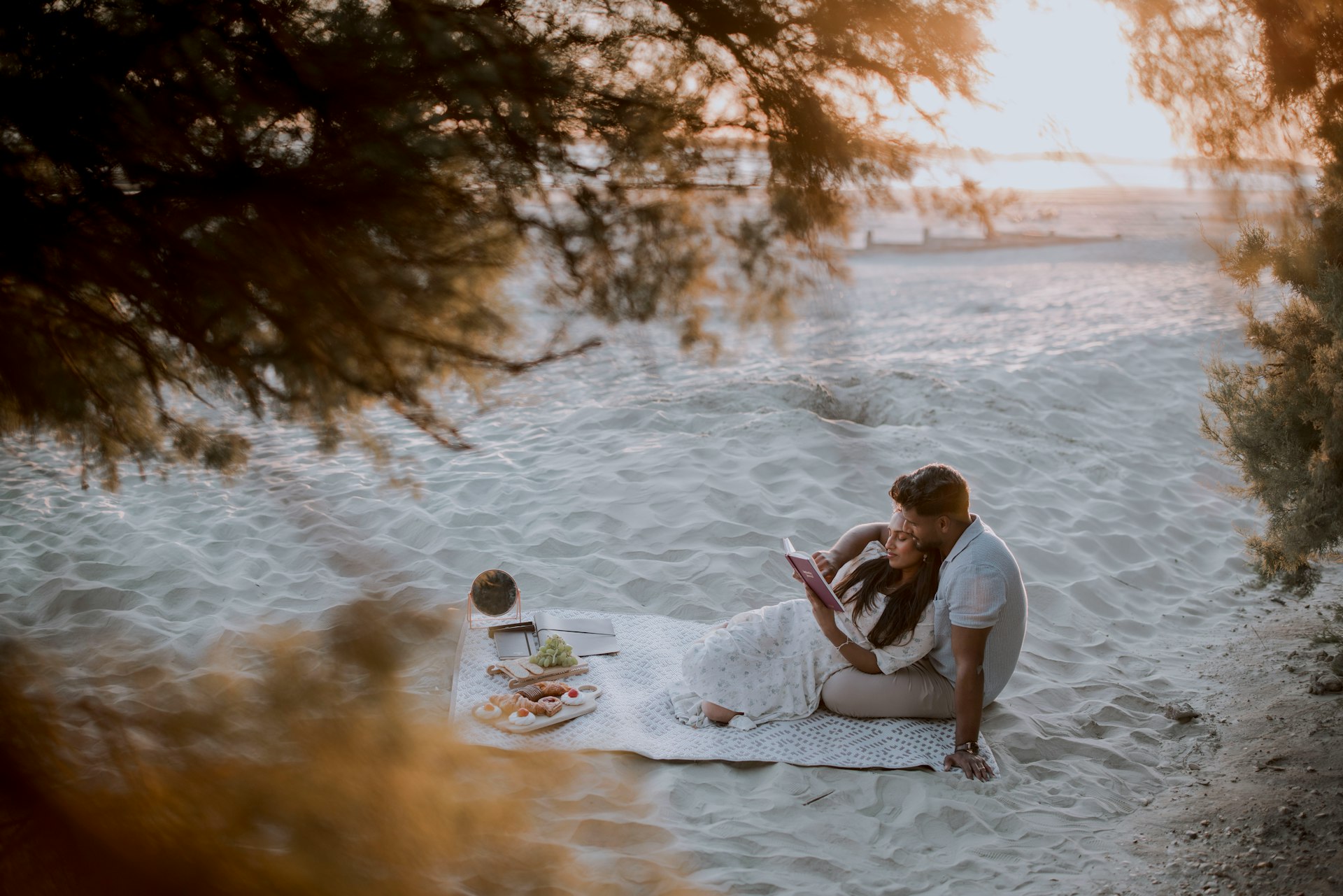 Couple enjoying a romantic picnic on a sandy beach.